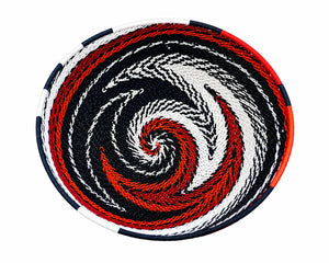 Hand-woven African telephone wire basket with a red, white, and black spiral pattern on a white background.