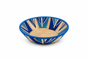 Handcrafted round woven basket bowl with blue and beige geometric patterns, isolated on white.